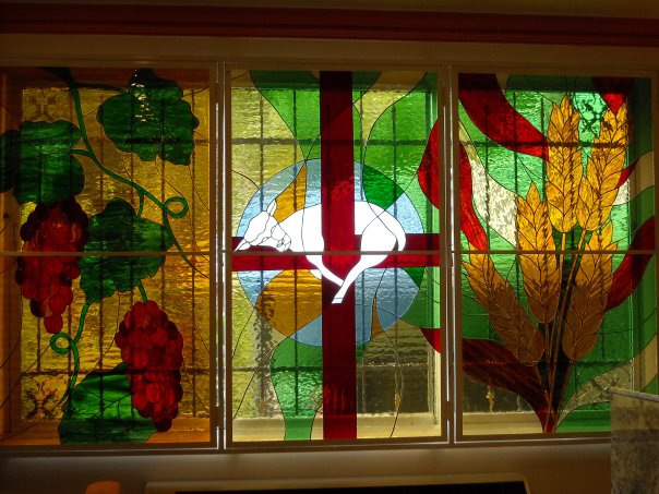 Custom stained glass chapel triptych featuring a lamb, grapevine and wheat sheaf