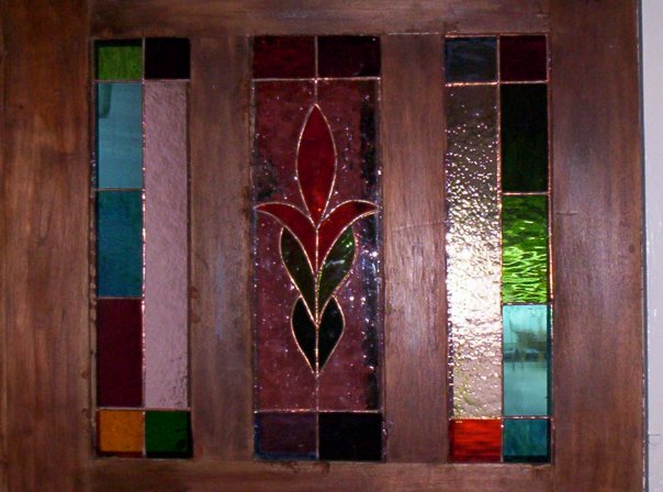 Stained glass door panel insert with a leaf motif in deep red, green and amber
