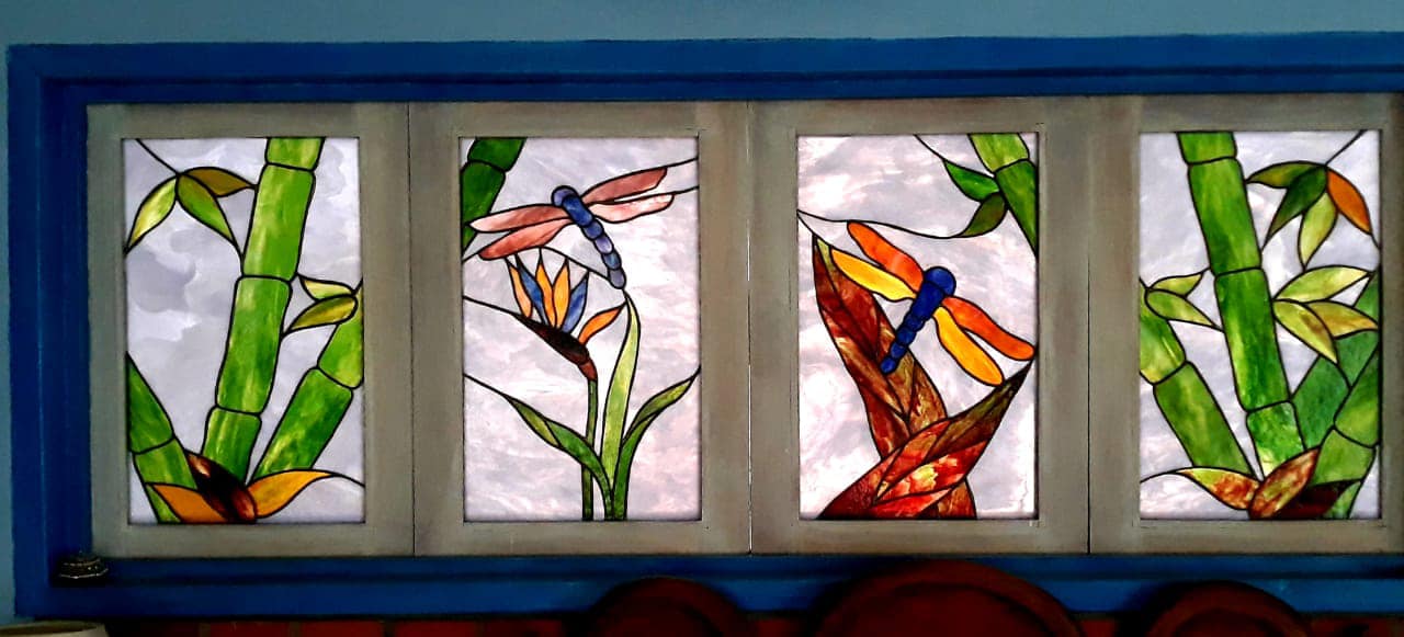 Four stained glass panels featuring bamboo, a dragonfly and a bird of paradise flower