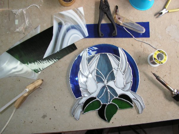 A custom stained glass bird design in progress on the work bench, mid-assembly